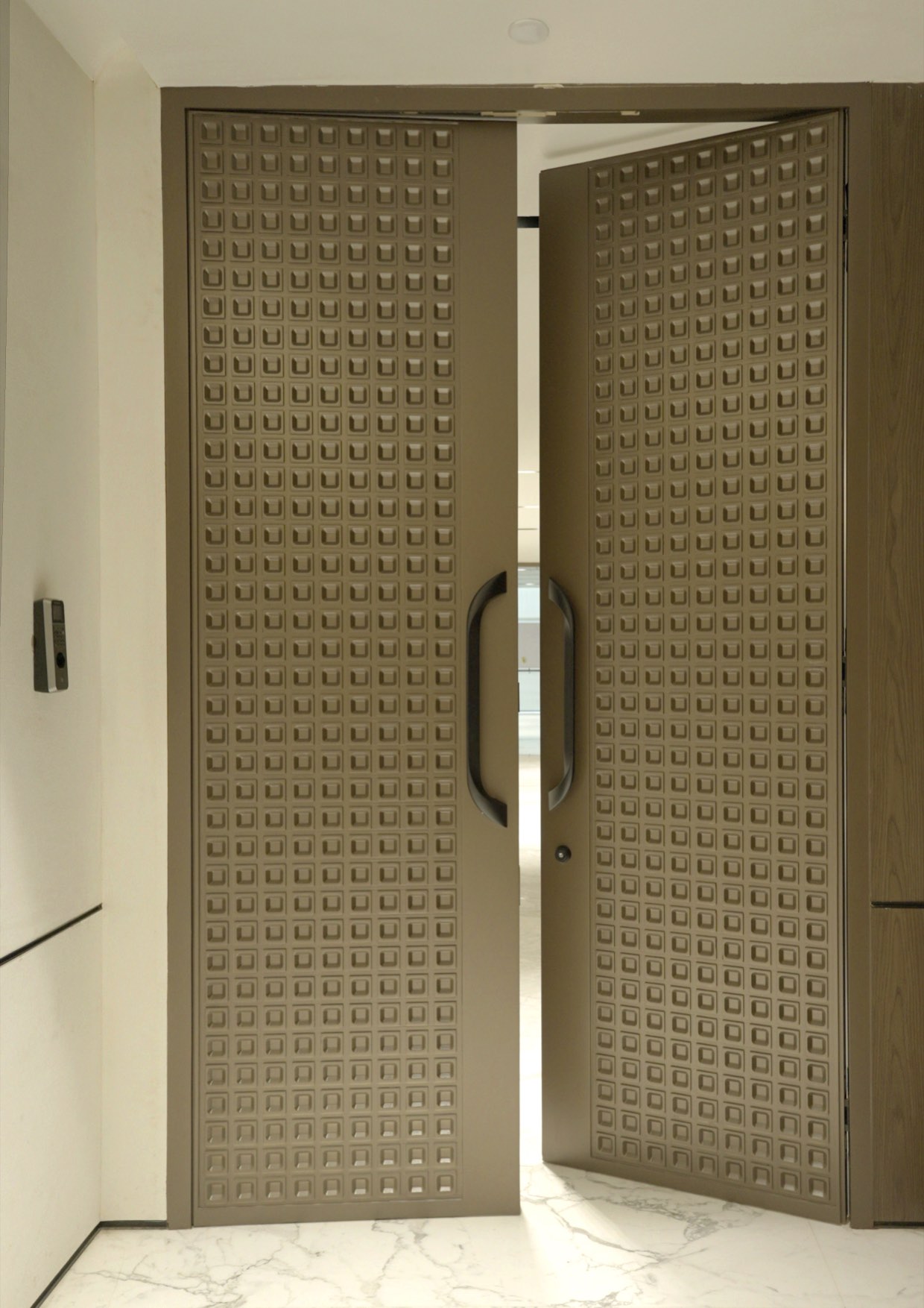 Tall panelled entrance doors standing open, with an access reader set into the wall beside them